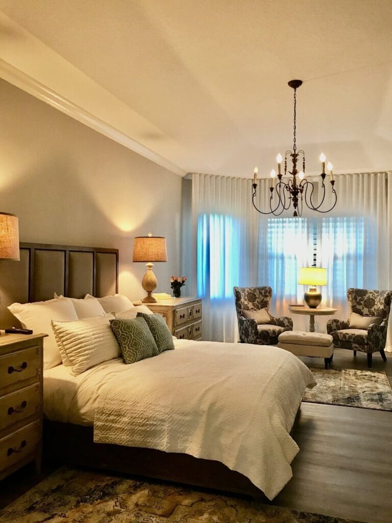 Bedroom with layered window treatments beside a wall of glass